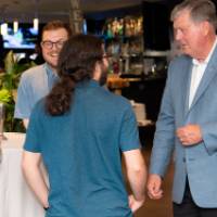 3 attendees talk with Tom Haas at event